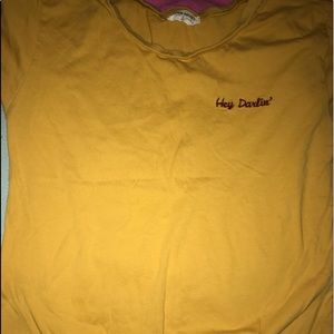 mustard yellow/orange top with a not on the bottom